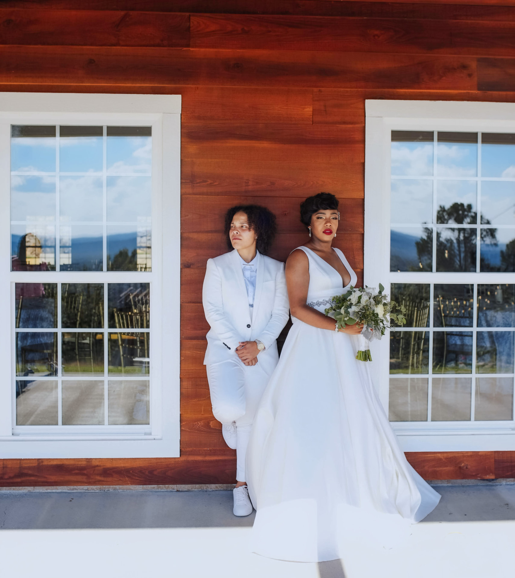 Two brides posing together outside their wedding venue