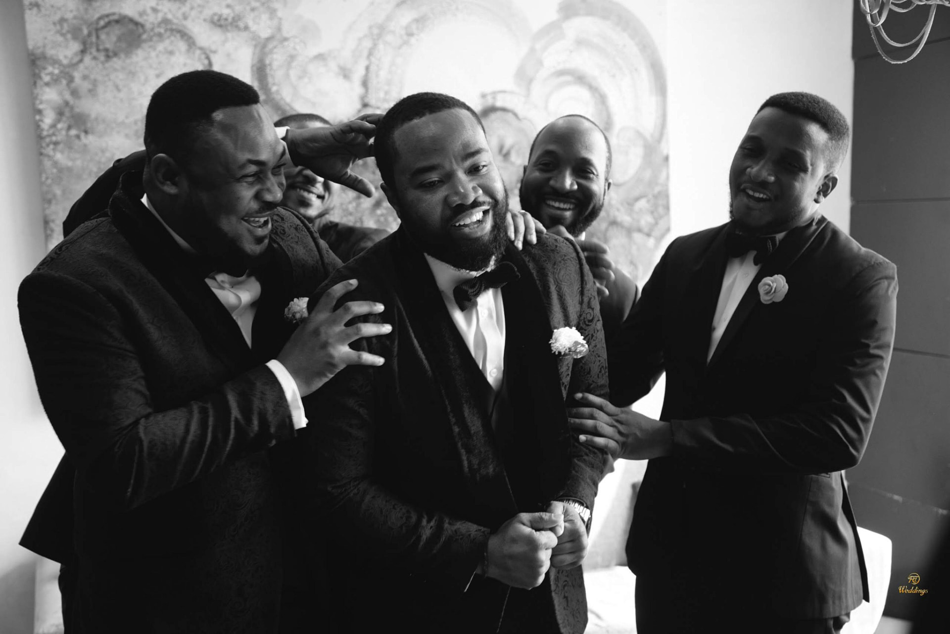 Black and white photo of the groom laughing with his groomsmen