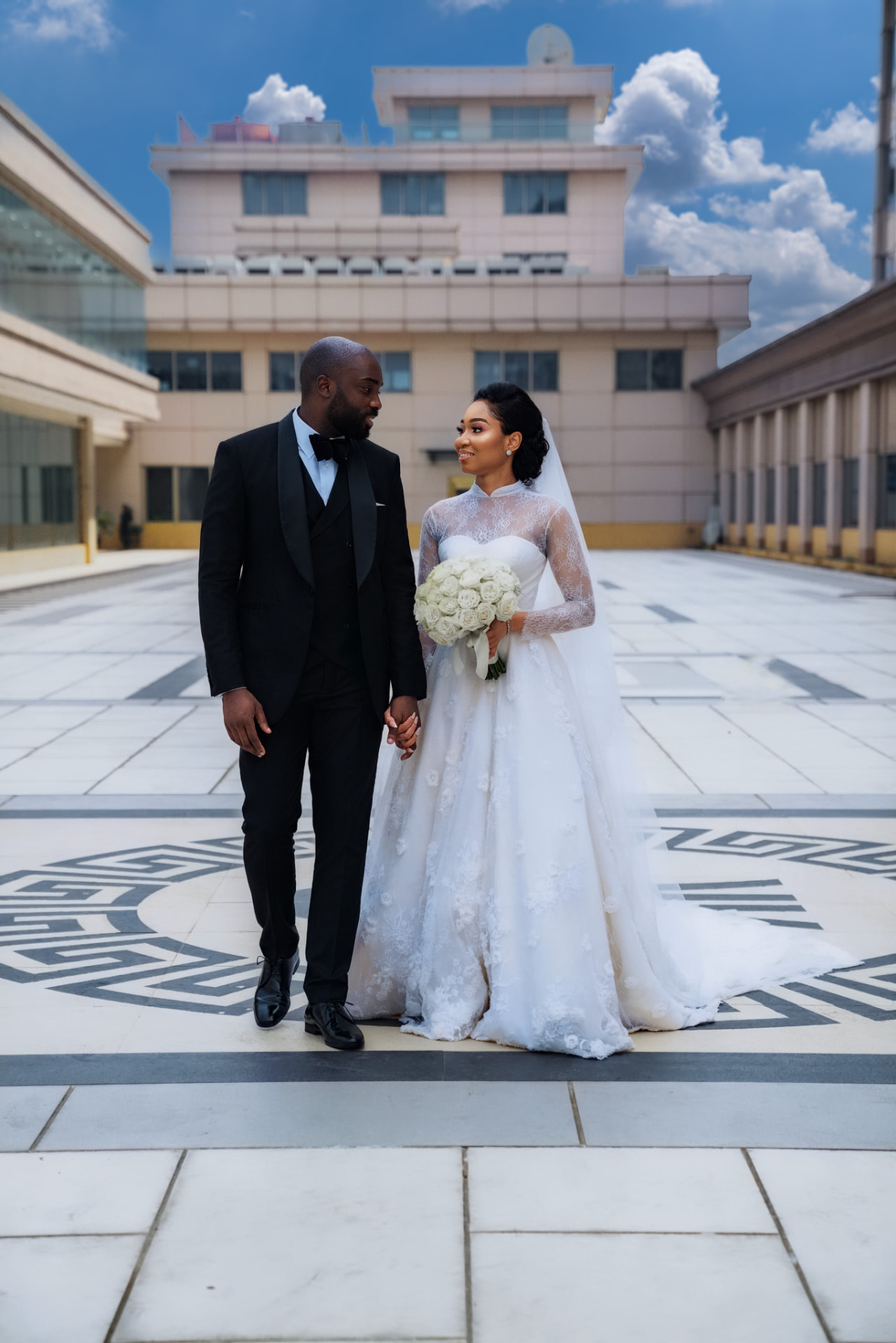 Bride and groom holding hands on a sunlit rooftop terrace
