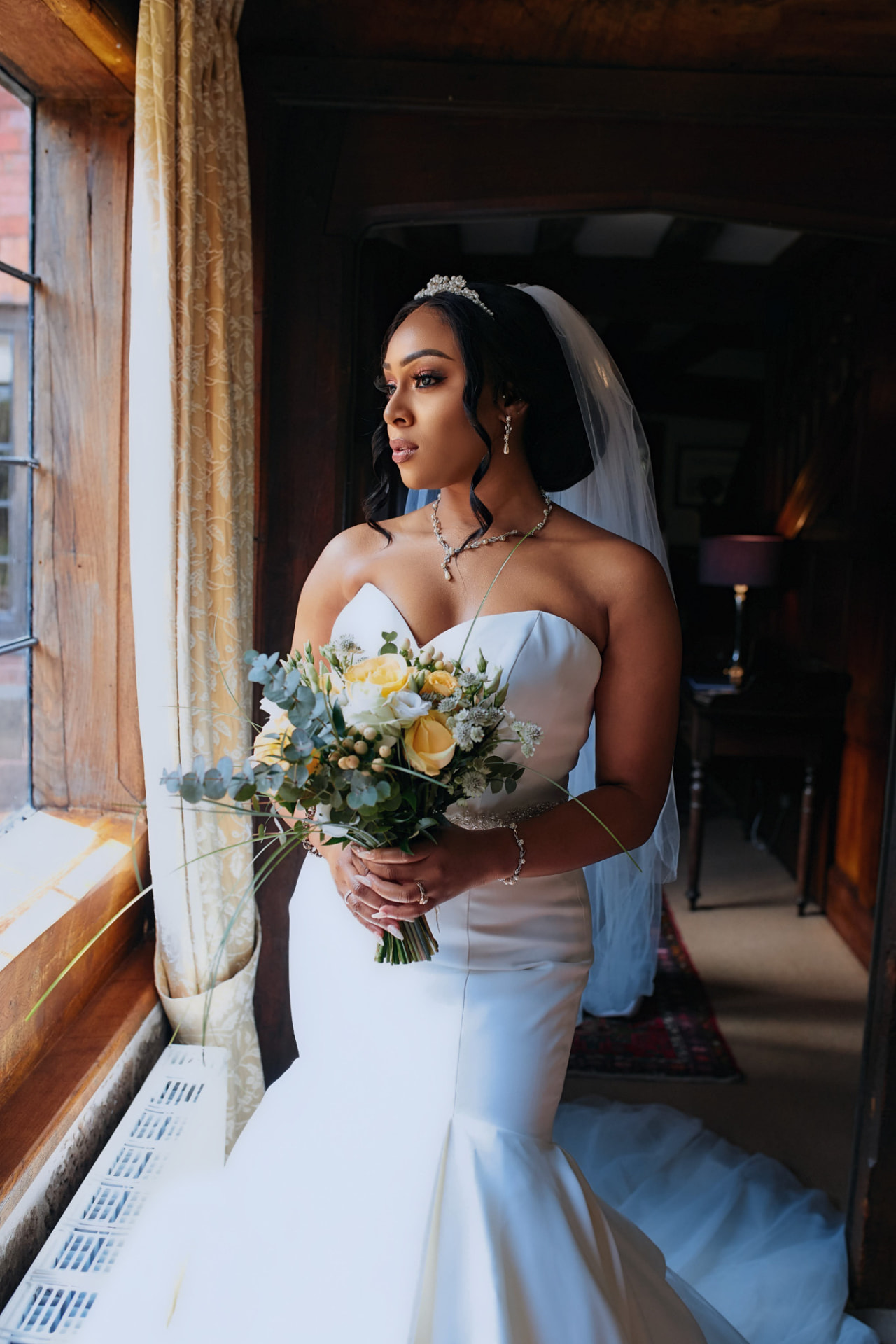 Bride looking out of a window in soft natural light